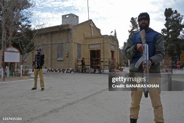 Policemen stand guard outside a church during the Christmas prayer service in Quetta on December 25, 2021.