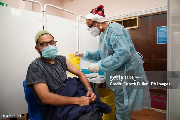 Correcting picture date to Saturday December 25, 2021 A man receives a 'Jingle Jab' Covid vaccination booster injection at Redbridge Town Hall, in...
