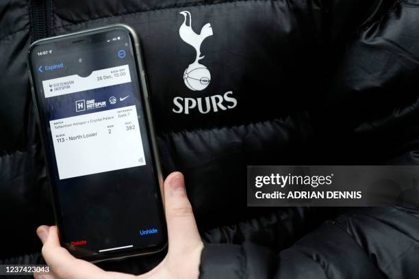 Fan shows his digital ticket on his mobile phone as he arrives for the English Premier League football match between Tottenham Hotspur and Crystal...