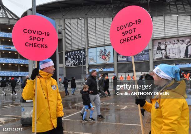 Stewards hold placards indicating Covid-19 spot checks ahead of the English Premier League football match between Manchester City and Leicester City...