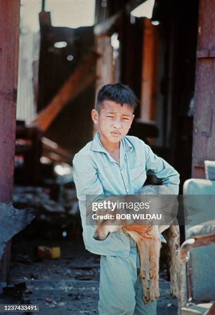 Young Vietnamese boy holds a dog in his arms on the streets of Kuong Tung, Vietnam, during the Vietnam War in 1967.