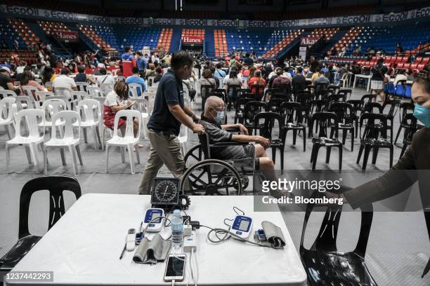 Visitor in a wheelchair is pushed at a vaccination site inside a gymnasium in San Juan City, Metro Manila, the Philippines, on Tuesday, Dec. 28,...