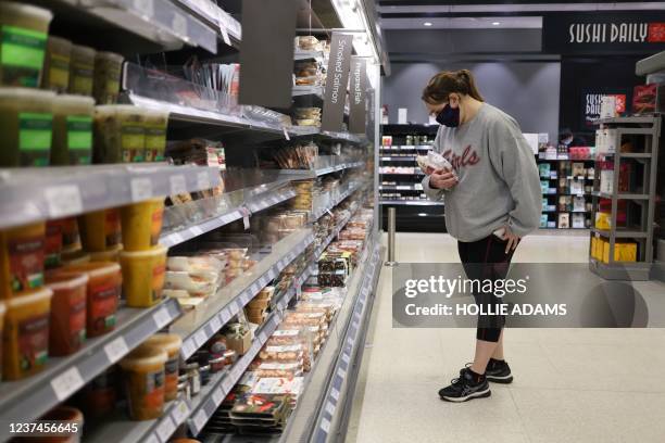 Woman shops for fish at a Waitrose supermarket in London on December 29, 2021. - British inflation has rocketed to its highest level for more than 10...