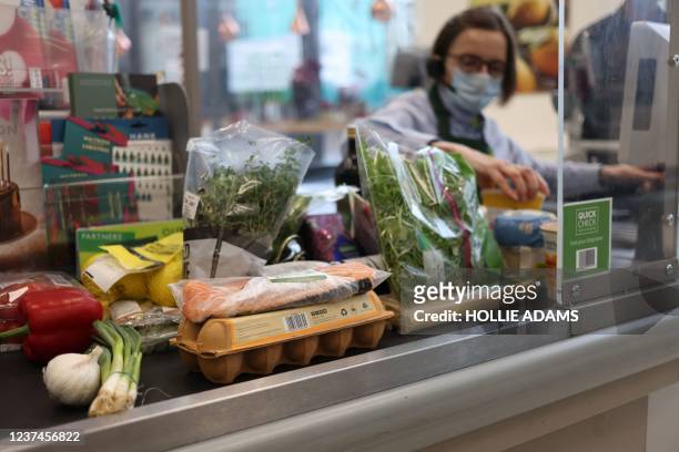 Cashier scans goods at a Waitrose supermarket in London on December 29, 2021. - British inflation has rocketed to its highest level for more than 10...
