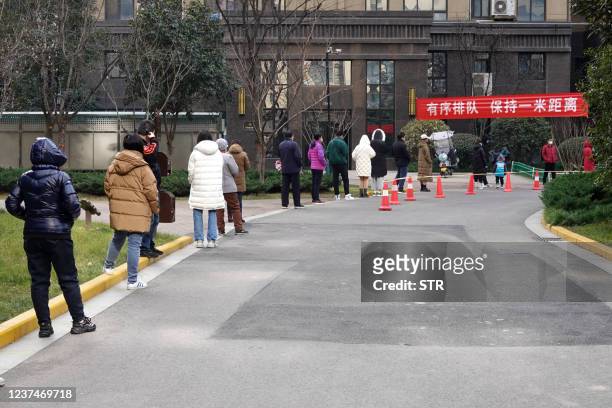 Residents queue to undergo nucleic acid tests for the Covid-19 coronavirus in Xi'an in China's northern Shaanxi province on December 30, 2021. -...