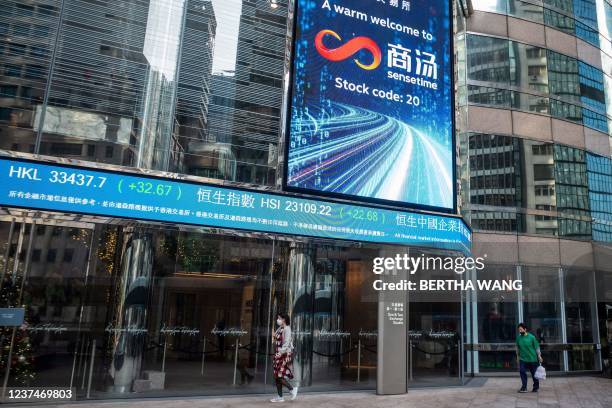 People walk beneath a welcome message for Chinese artificial intelligence start-up SenseTime after listing on the stock exchange in Hong Kong on...