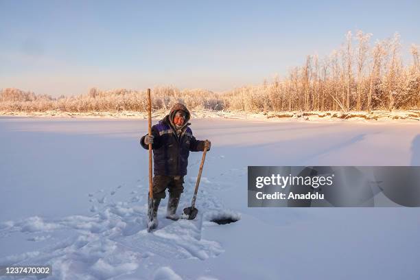 Man wears thick clothes while ice fishing as temperature dropped to 60 Celsius degrees below 0 in Russia's Oymyakon province on December 24, 2021.