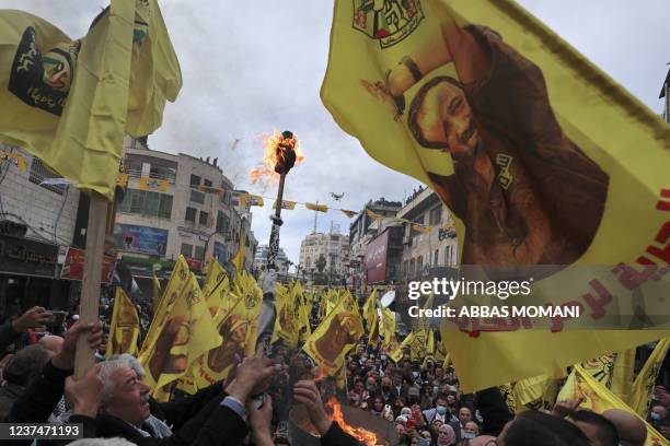 Palestinians wave banners bearing the image of jailed Fatah leader Marwan Barghuti with a slogan demanding his release and referring to him as the...