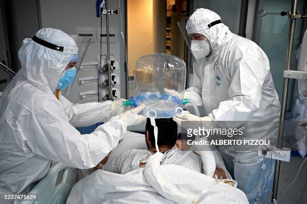 Medical staff members help a patient to wear a new non-invasive technology that can reduce the need of intubation at Covid-19 intensive care unit at...