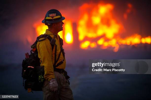 Mountain View wildland firefighter walks through the smoke and haze after a fast moving wildfire swept through the area in the Centennial Heights...