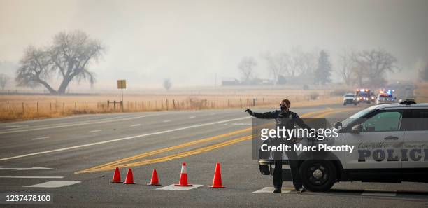 Louisville Police Officer directs traffic away from a closed road as fast moving wildfires forced multiple evacuations and road closures on December...
