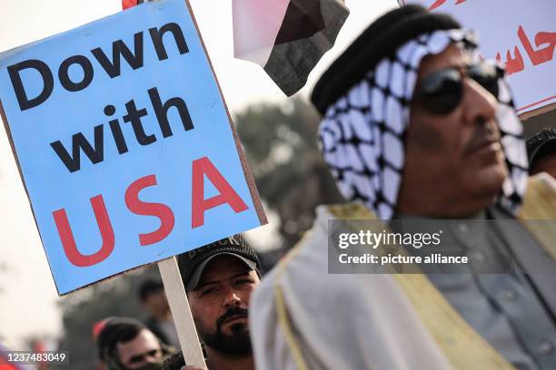 December 2021, Iraq, Baghdad: An Iraqi man holds up a sign reading "Down with USA) during a rally staged by supporters of Asa'ib Ahl al-Haq Shia...