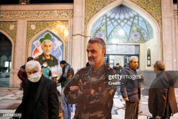 People walk past a cutout depicting the slain top commander of the Iranian revolutionary guard corps , Qasem Soleimani, on display in the courtyard...