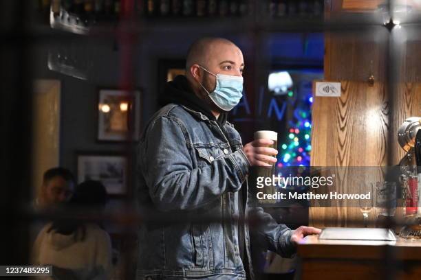 Man wearing s face mask holds a pint in Central Bar on December 31, 2021 in Cardiff, Wales. The countries that make up the UK have differing covid...