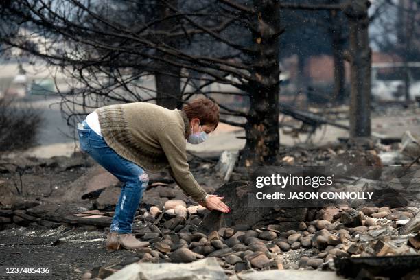 Judy Delaware searches through the remains of her home for an engraved stone with the words Welcome in The Enclave neighborhood of Louisville,...