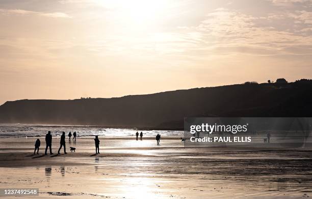 People take a New Year's Day walk on the South Bay Beach in Scarborough, north east England on January 1, 2022.