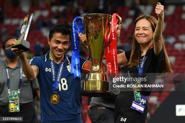 Thailand's Chanathip Songkrasin poses with the AFF Suzuki Cup 2020 football tournament trophy and Most Valuable Player award and team manager...