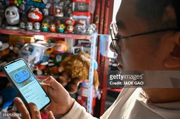 The photo taken on December 30, 2021 shows Olympic superfan Zhang Wenquan looking at Paris 2024 Olympic souvenirs on eBay at his home in Beijing. -...