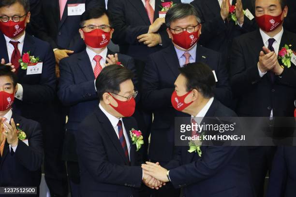 Yoon Suk-yeol , the presidential election candidate for South Korea's main opposition People Power Party , shakes hands with Lee Jae-myung , the...
