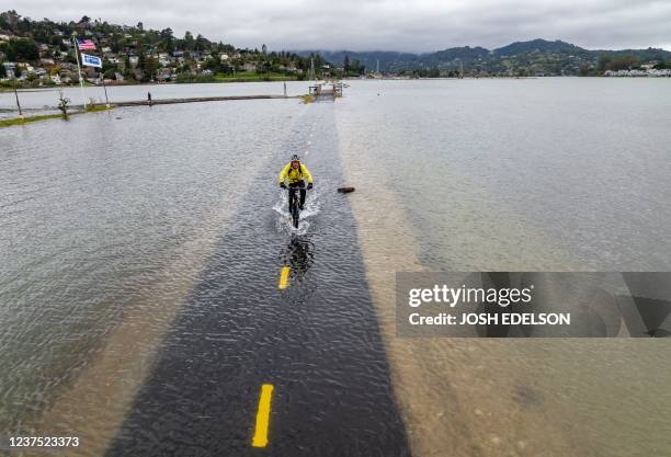 An aerial picture taken on January 3 shows a man riding his bike along a flooded Sausalito/Mill Valley bike path during the "King Tide" in Mill...