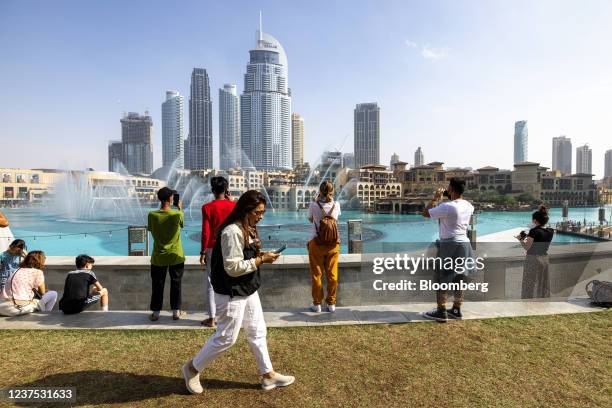 Tourists watch the water fountain display near the Burj Khalifa skyscraper, in Dubai, United Arab Emirates, on Sunday, Jan. 2, 2022. Dubai set out...