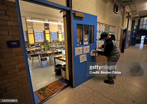 Boston, MA Juan Montes, a senior custodian, cleans a classroom doorknob at the Donald McKay K-8 school in East Boston on Jan. 3, 2022.