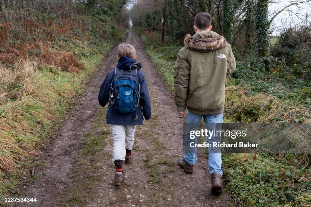 Young 12 year-old boy and his mid-20s cousin walk along an old drovers' route in the Somerset countryside on Boxing Day, on 26th December 2021, in...
