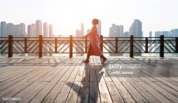 woman walking on the boardwalk by the sea - woman side view walking stock pictures, royalty-free photos & images