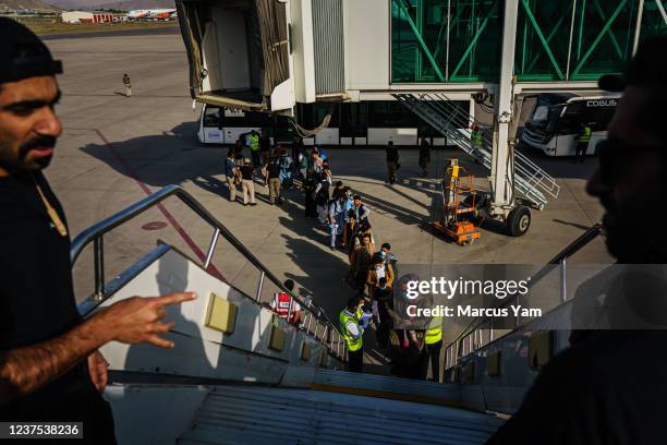Afghans prepare to board the evacuation flight out of the country, with other Afghan nationals, at the airport, in Kabul, Afghanistan, Sunday, Oct....