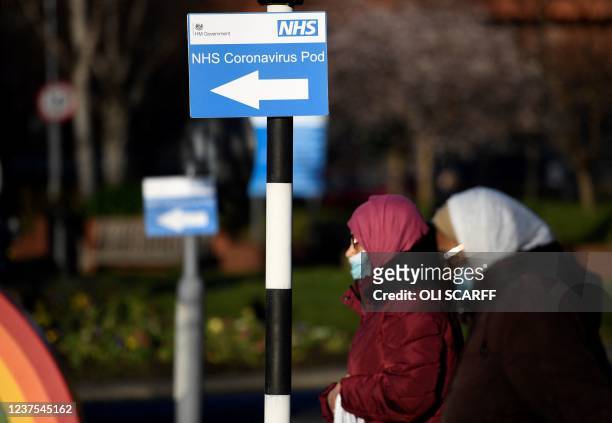 Pedestrians walk past a sign for a NHS Coronavirus Pod outside St James's University Hospital in Leeds, northern England on January 5 where a...