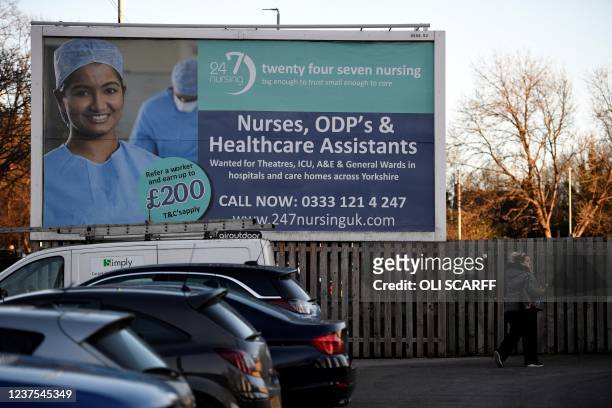 Pedestrian walks past a job advertisement for Nurses, ODP's and Healthcare Assistants, opposite St James's University Hospital in Leeds, northern...