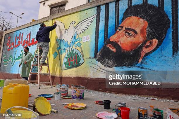 Palestinian artists draw a mural of Hisham Abu Hawash, a Palestinian prisoner who ended his hunger strike after Israel committed to his eventual...
