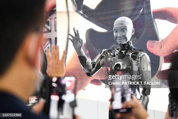 Attendees take pictures and interact with the Engineered Arts Ameca humanoid robot with artificial intelligence as it is demonstrated during the...