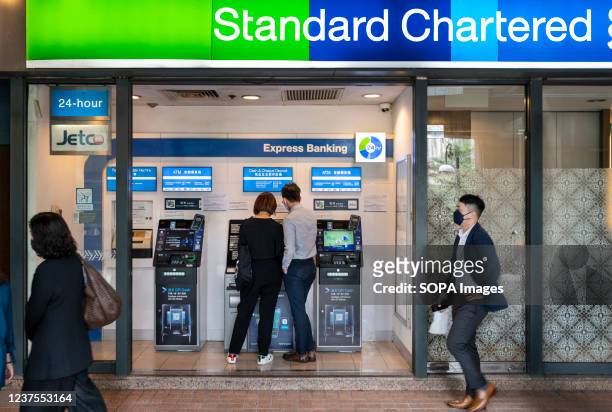 Pedestrians walk past the British multinational banking and financial services company Standard Chartered branch in Hong Kong.