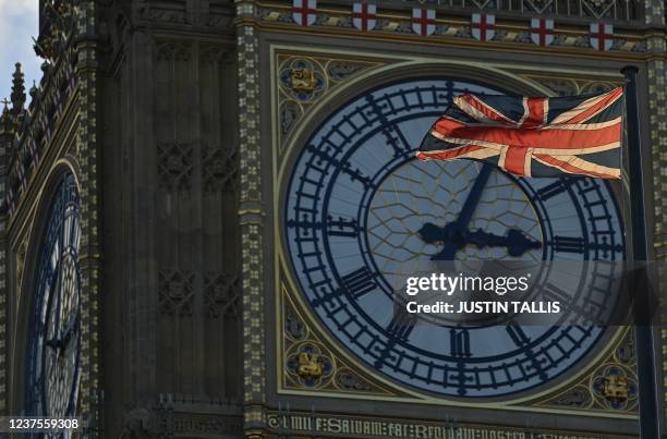 Union Flag flies in front of the clock face on Elizabeth Tower, commonly known by the name of the bell Big Ben, at the Palace of westminster while...