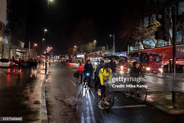 Night scene in Blackfriars of commuter cyclists waiting at the traffic lights on Blackfriars Bridge on 7th December 2021 in London, United Kingdom....