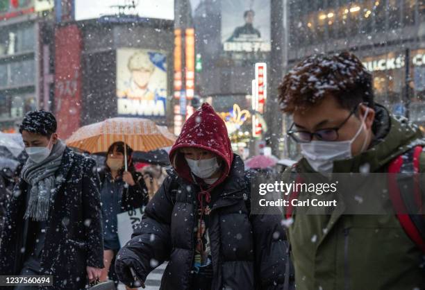 People walk along Shibuya crossing during snowfall on January 6, 2022 in Tokyo, Japan. Tokyo was blanketed in snow today as a low-pressure weather...