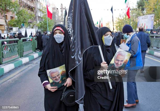 Iranian mourners hold pictures of slain top Iranian commander Qasem Soleimani in Tehran during a funeral procession for 150 Iranian soldiers killed...