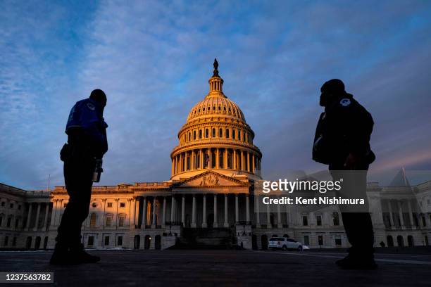 Capitol Police Officers stand on the East Plaza of the Capitol Campus as the dome of the U.S. Capitol Building is illuminated by the rising sun on...