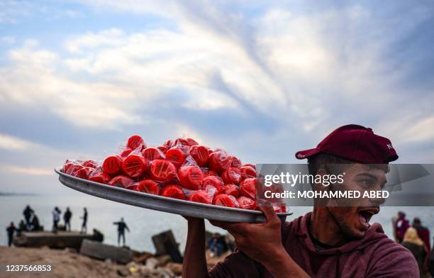 Palestinian vendor yells to attract customers as he sells sugar-coated apples along the beach in Gaza City, on January 6, 2022.