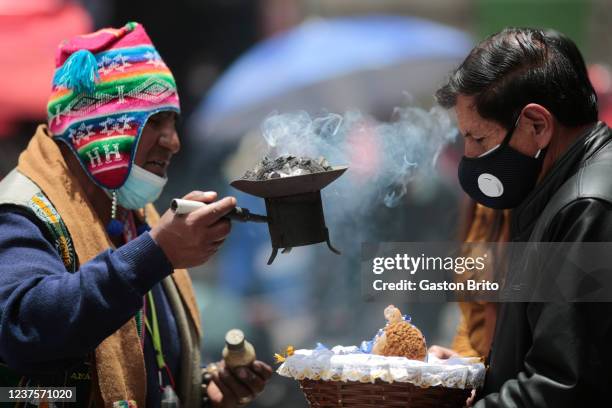 Witchdoctor moves a brazier with burned incense over a basket with an image of baby Jesus during the mass of the Wise Men as part of the Three Wise...
