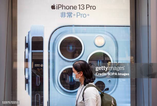Pedestrian walks past an American multinational technology company Apple Iphone 13 Pro commercial advertisement in Hong Kong.