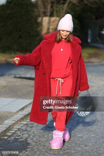 Cathy Hummels wearing a red teddy coat by Max Mara, red jogging suit by Revolve, pink Moon boots, Clutch by Louis Vuitton, new collection, during a...