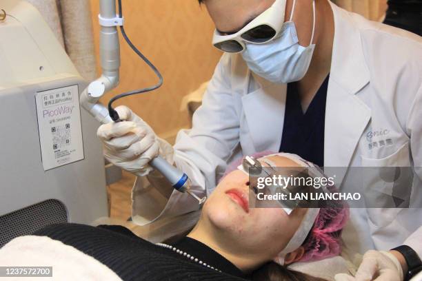 This photo taken on November 11, 2021 shows Kayla Zhang, a finance worker, receiving laser facial treatment at a beauty clinic in Shanghai. - Already...