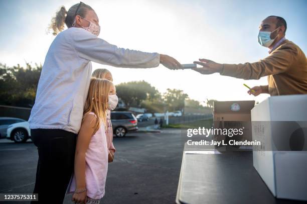 Redondo Beach, CA Jennifer Kahn, with daughters Kate,5 and Elyse picks up an iHealth COVID-19 Antigen Rapid Test kit allotted for Kate, from Tulita...