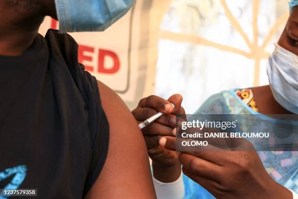 Nurse administers a Covid-19 vaccine to a person at the Palais des Sports vaccination centre in Yaounde on January 6, 2022. - A Covid-19 vaccine is...