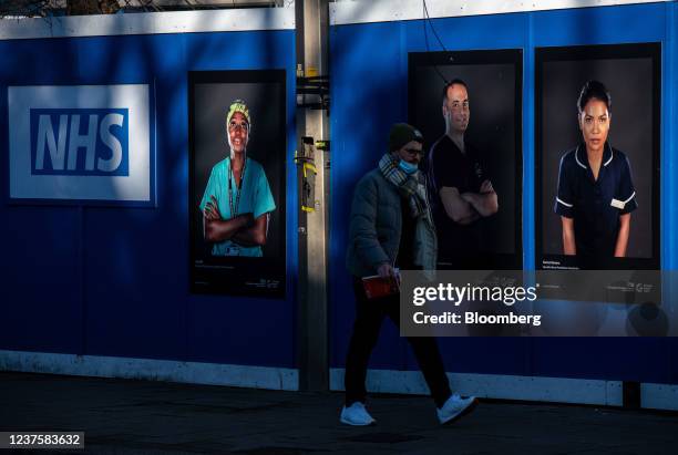 Pedestrian passes portraits of National Health Service workers on hoardings outside a temporary structure, to be used a so-called Nightingale care...