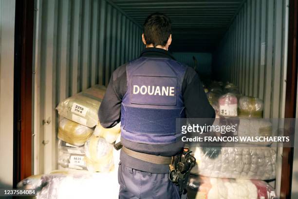 Belgian customs officers and dog search for drugs in a container at Antwerp's port, on January 7, 2022. - The amount of cocaine seized in Europe's...