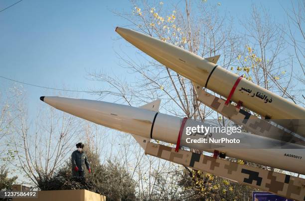 An Islamic Revolutionary Guard Corps military personnel stands under the Iranian solid-propelled road-mobile single-stage missile, Zolfaghar Basir...