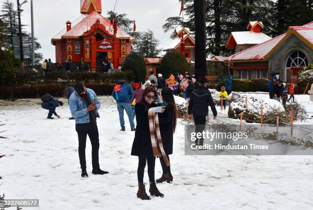 Tourists take pictures after the seasons first snowfall at Jakhoo on January 8, 2022 in Shimla, India.